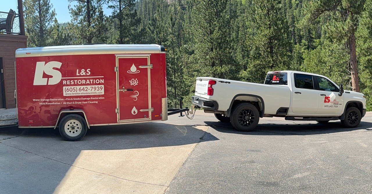 L&S Restoration branded red trailer and white pickup truck parked in the Black Hills